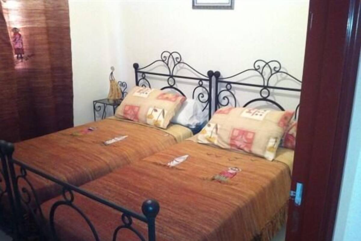 A bed with a metal frame, two pillows, and a brown bedspread.