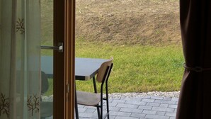 Ein Zimmer mit Blick auf einen grasbewachsenen Hügel und einen Baum.