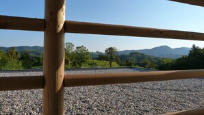 Eine Holzhandläufe mit Blick auf eine Kiesfläche und ferne Berge.