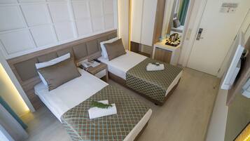 Habitación de hotel con dos camas, un escritorio pequeño, un espejo y una puerta.
