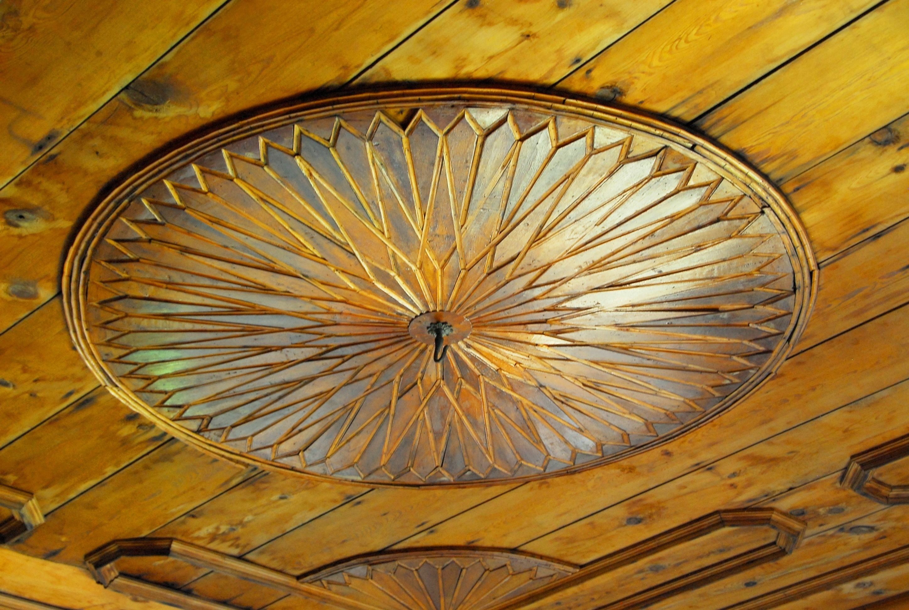 A wooden ceiling with a circular, geometric-patterned design.