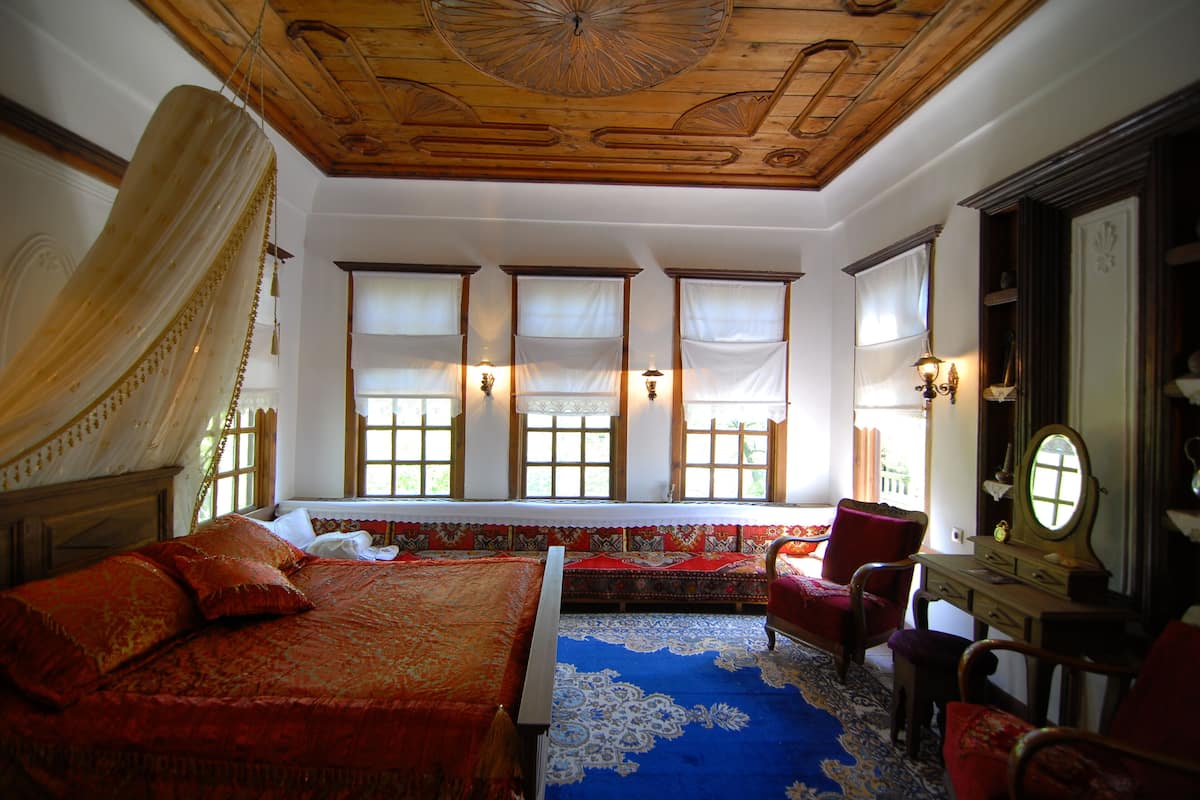 A room with a large bed, a wooden ceiling, and a window with a view.