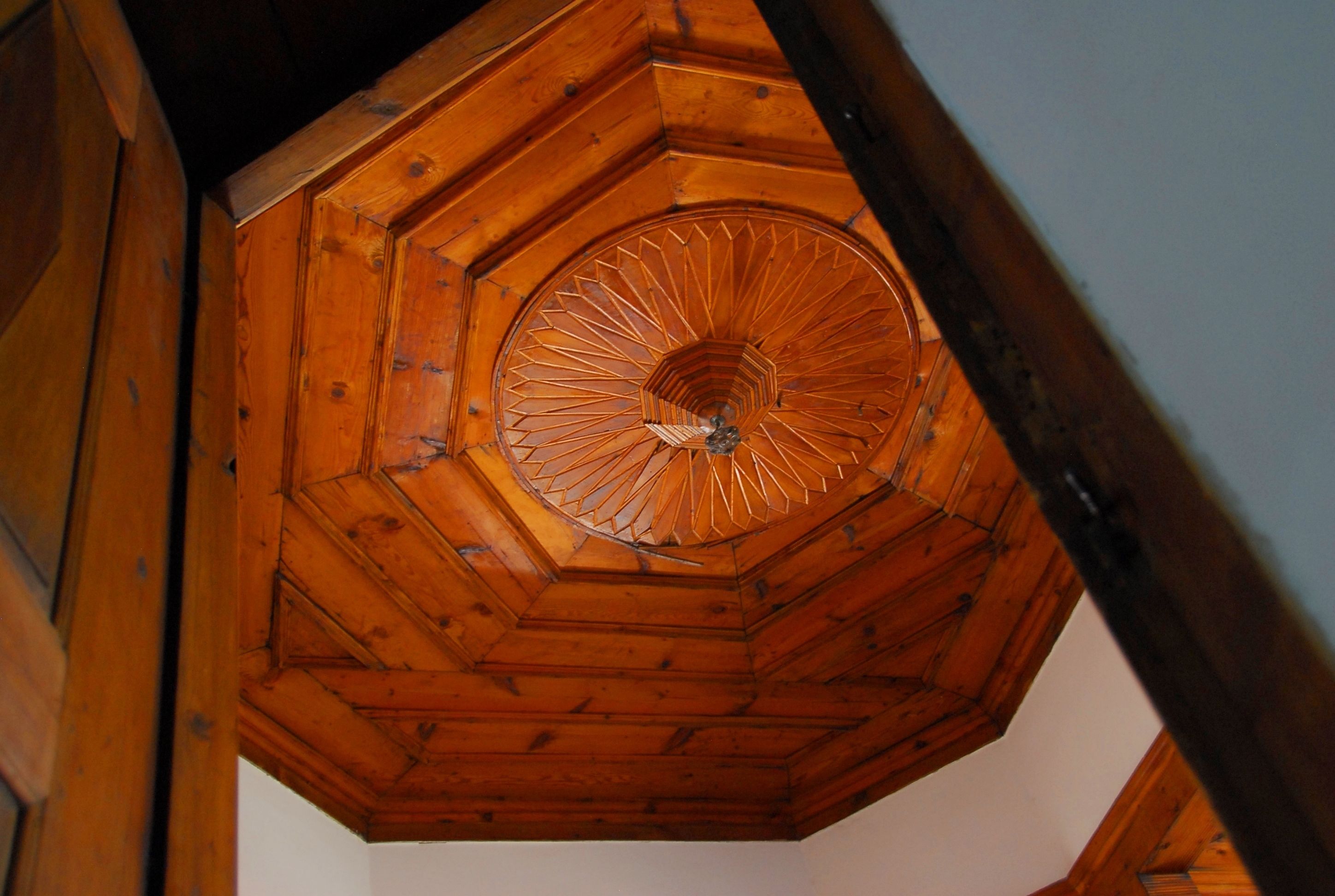 A wooden ceiling with a circular design and a central decorative element.
