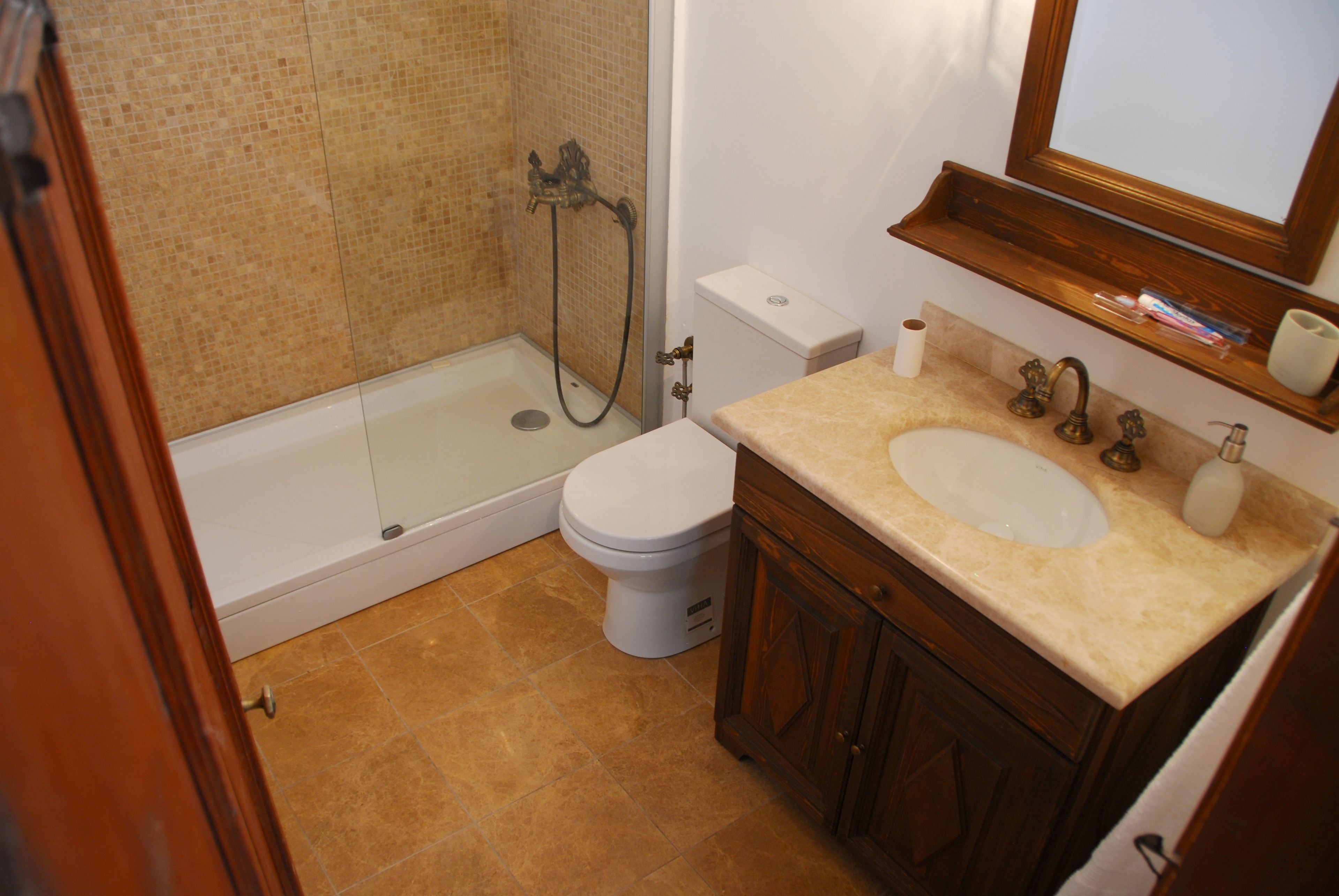 A bathroom with a shower, toilet, sink, and wooden cabinets.