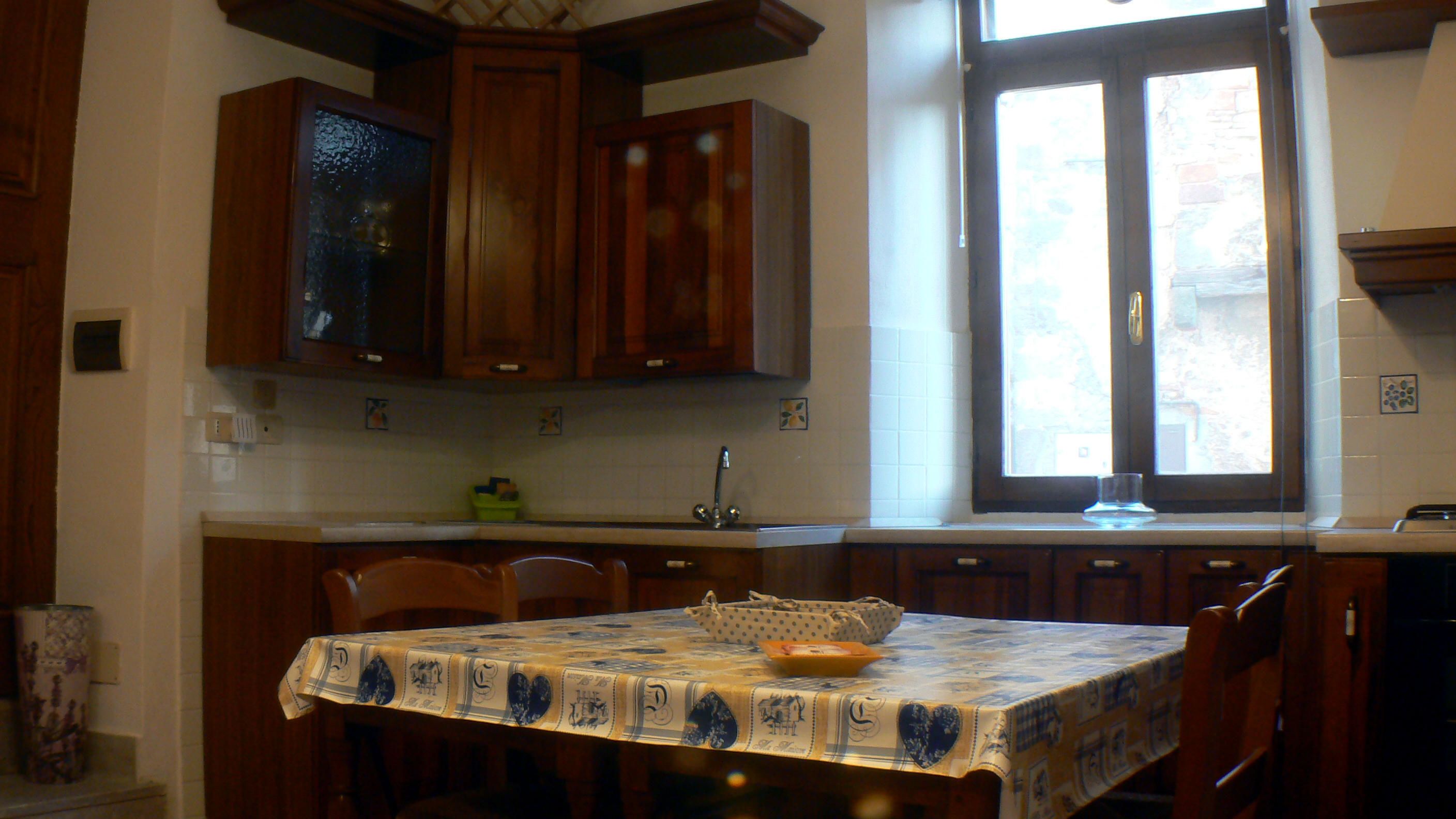 A kitchen with wooden cabinets, a window, and a table with a tablecloth.