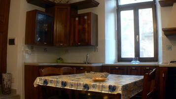 A kitchen with wooden cabinets, a window, and a table with a tablecloth.
