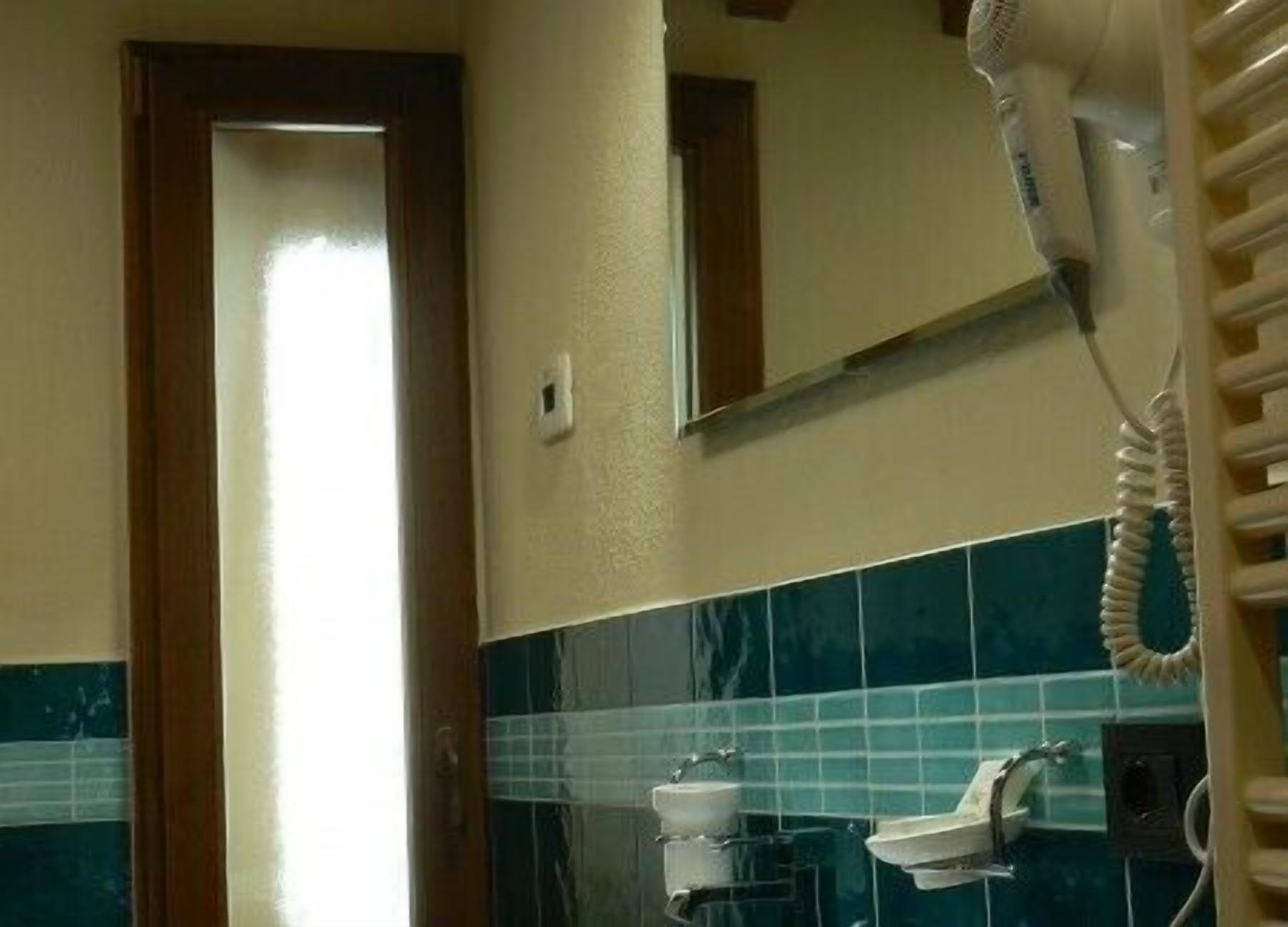 A bathroom with a hairdryer, a sink, and a mirror.