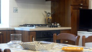 A kitchen with a stove, oven, and dining table with chairs. - Thalassa Locanda B&B e Appartamento (Arcidosso)