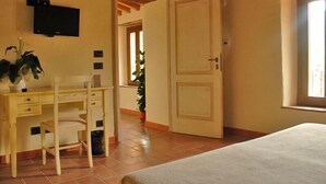 A bedroom with a bed, a desk, and a chair. There is a door leading to another room and a window with a view. - Thalassa Locanda B&B e Appartamento (Arcidosso)