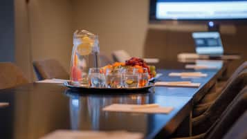 A conference table with a pitcher of water, glasses, and a fruit platter.