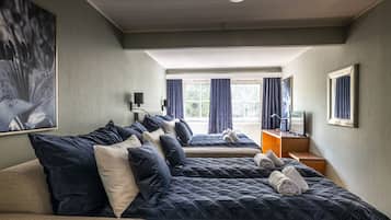Et hotelværelse med en stor seng, en mindre seng, en sofa, et skrivebord og et vindue med gardiner.