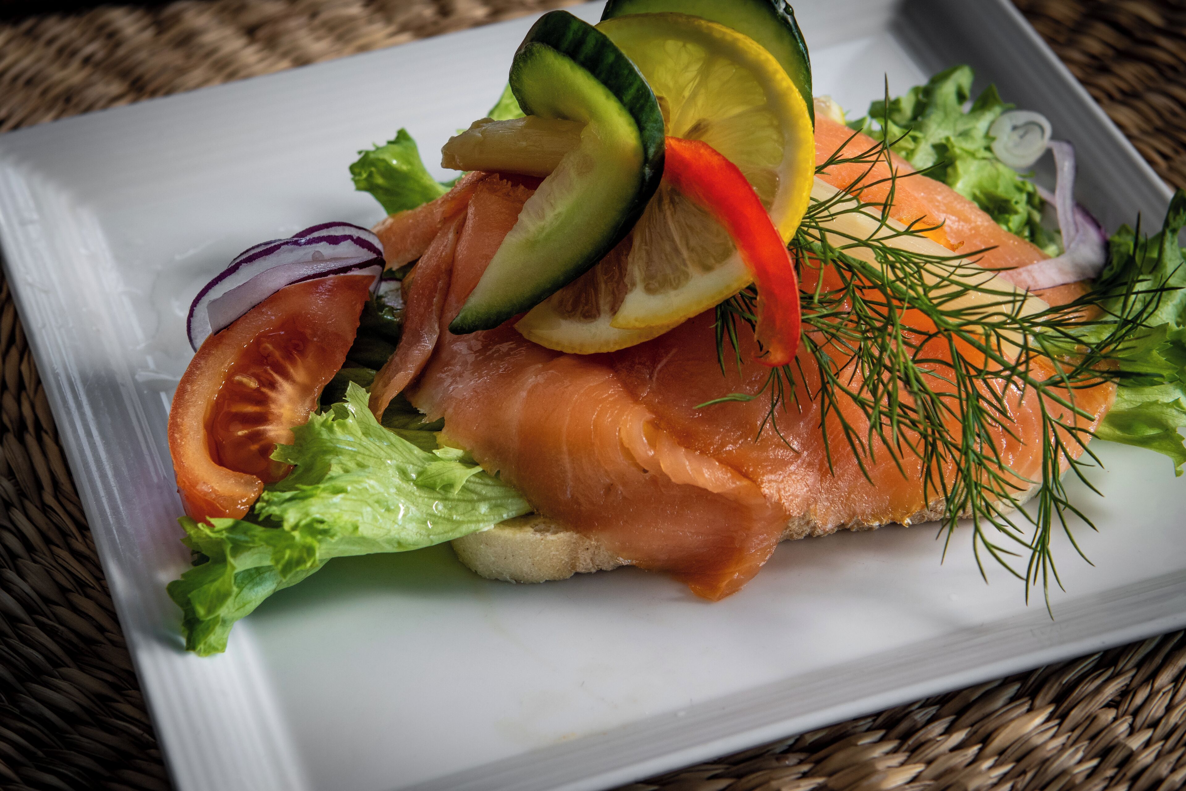 A plate of food with salmon, vegetables, and a slice of bread.