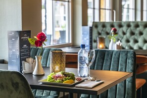 Un ambiente de restaurante con un menú, una botella de agua, una copa de vino y un plato de comida.
