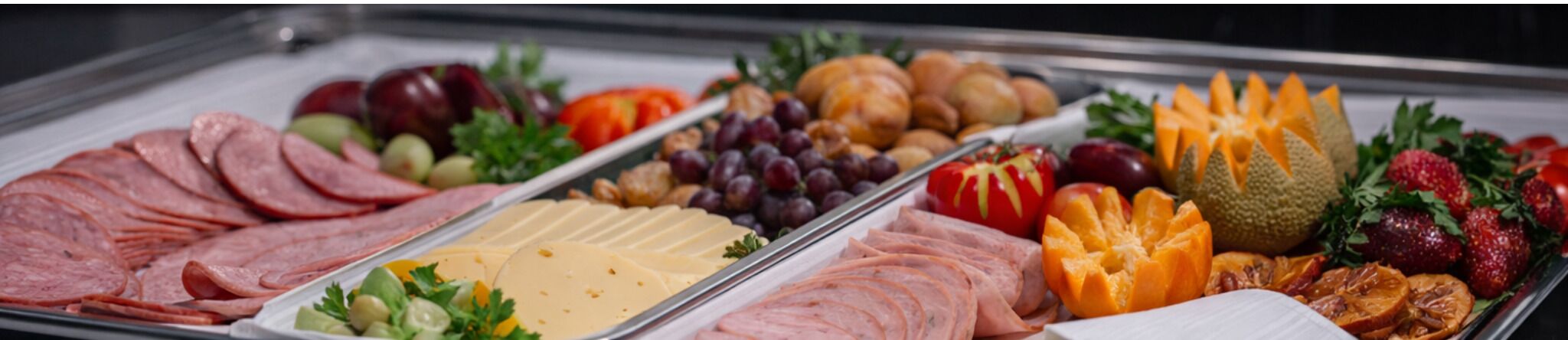Un bufé con diferentes carnes, quesos, frutas y verduras.