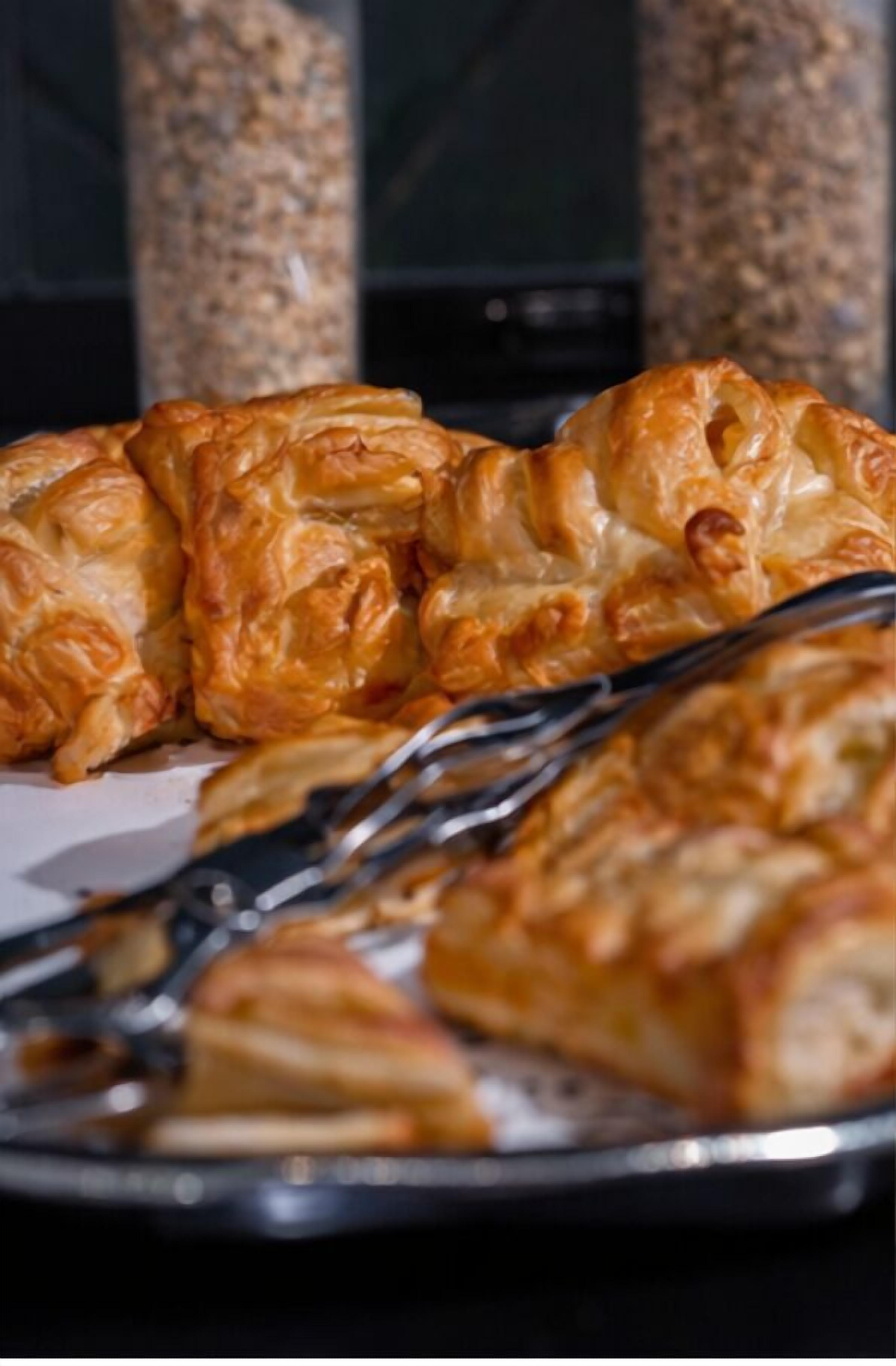 A tray of golden-brown pastries with a flaky texture, accompanied by a fork.