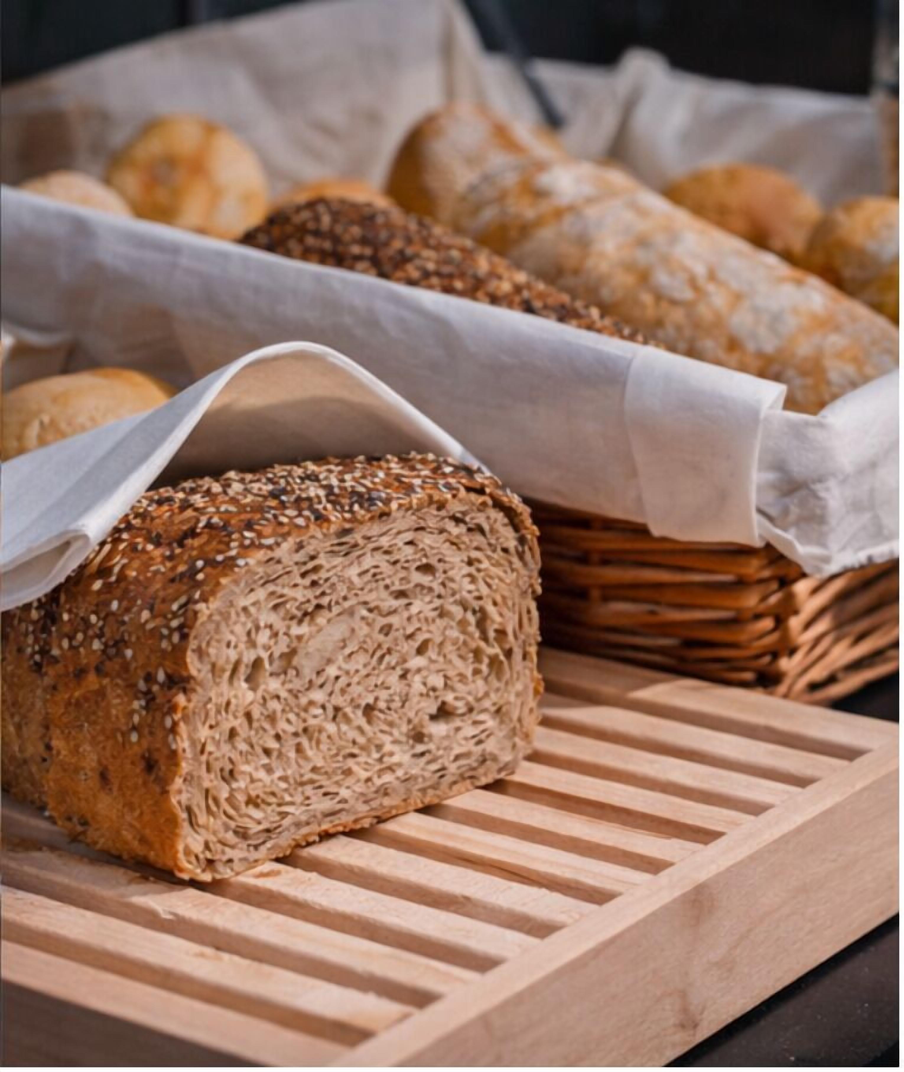 A loaf of seeded bread on a wooden cutting board.