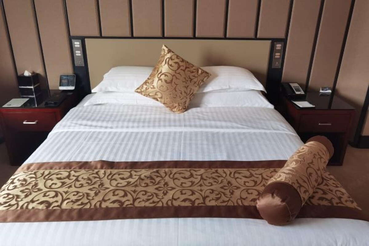 A neatly made bed with a patterned pillow and a decorative bed runner.