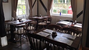 Una posada tradicional con muebles de madera, varios ventanales con cortinas y una decoración rústica.
