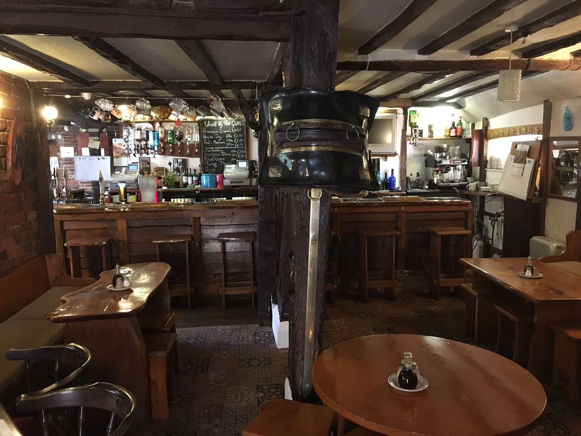 A rustic bar area with wooden furniture, a chalkboard menu, and various bottles.