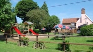 Un parque infantil con toboganes y zona de picnic con sombrillas.