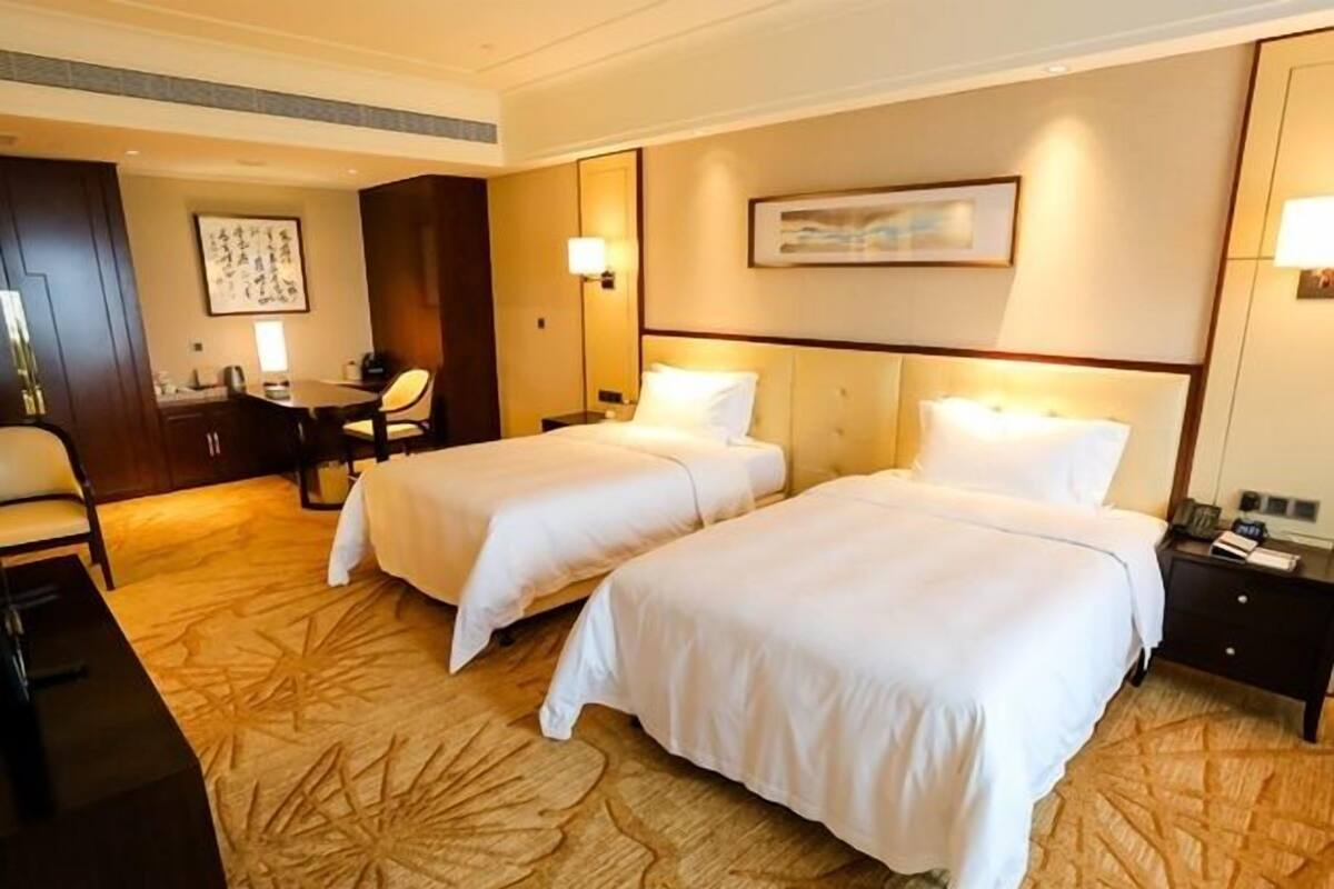 Une chambre d’hôtel avec deux lits, un bureau, une chaise et une petite table.