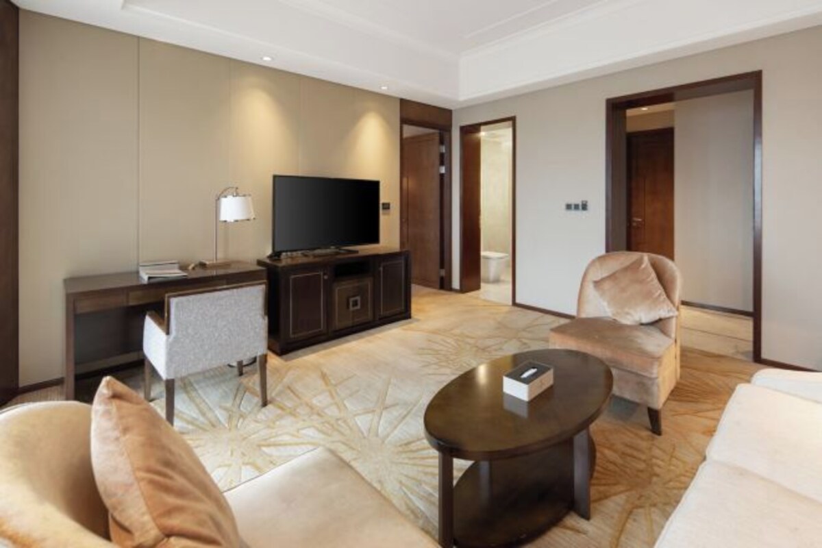 Een moderne hotelkamer met een flatscreen-televisie, een bureau, een bank en een salontafel.