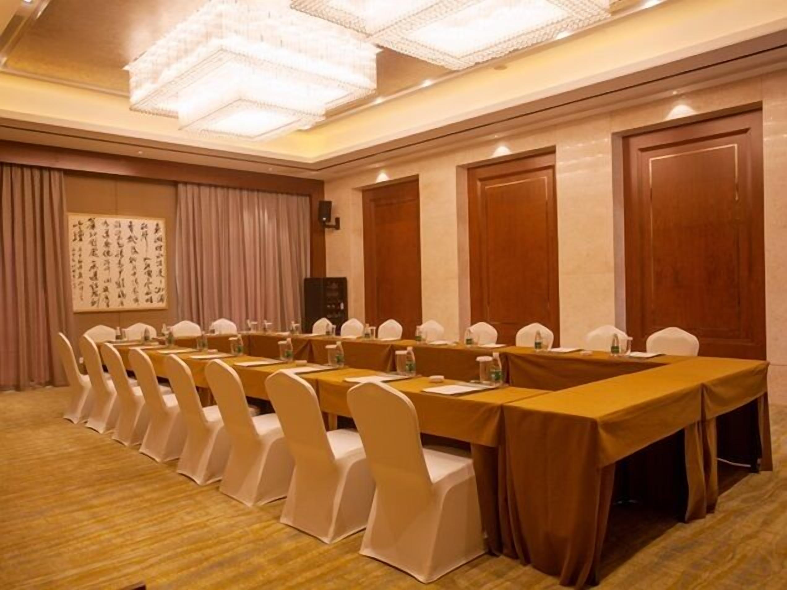 A conference room with a long table, white chairs, and a chandelier.