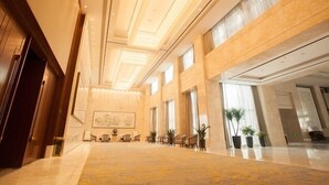 Eine geräumige Lobby mit hoher Decke, großen Fenstern und einem Teppichboden.