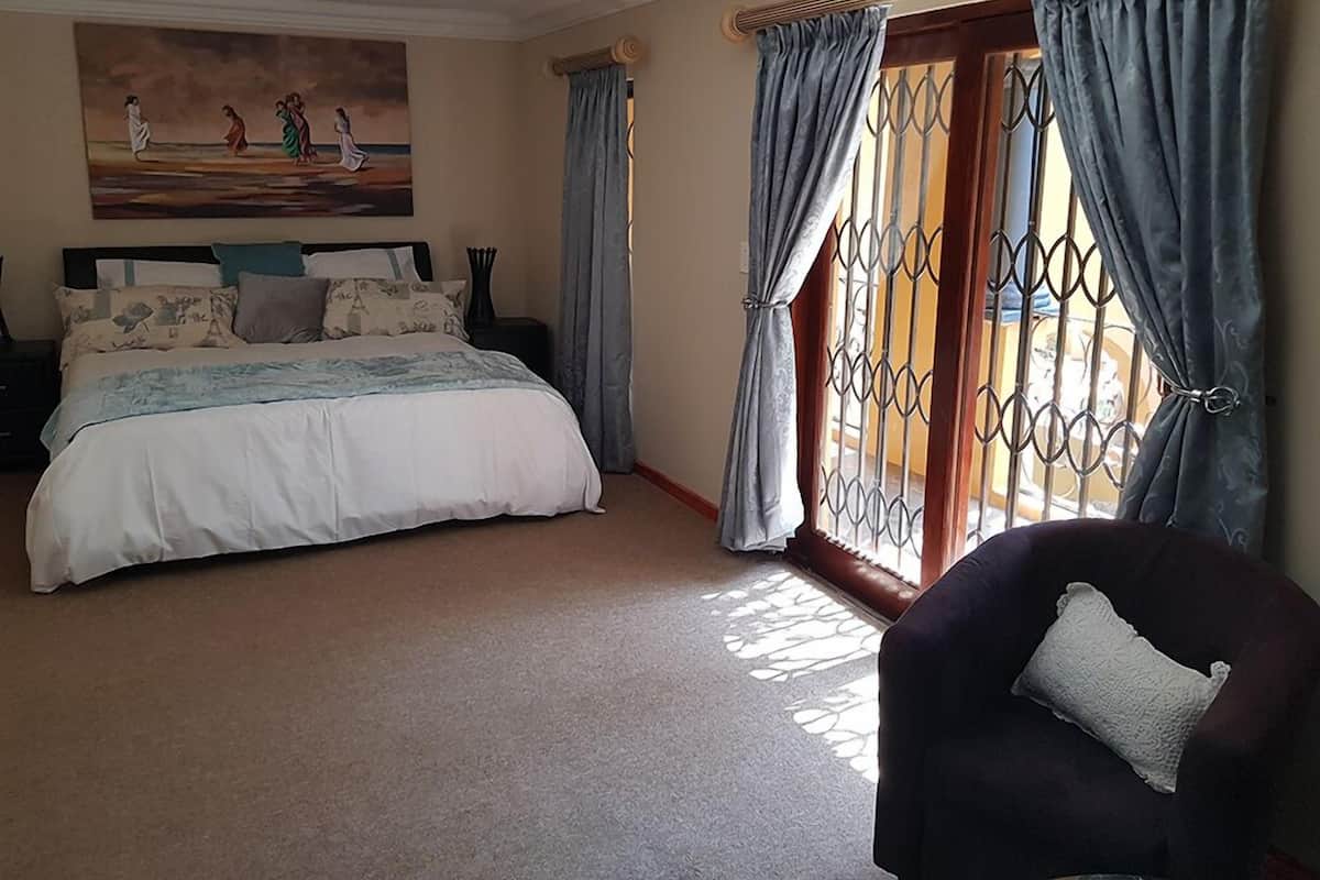 Ein Schlafzimmer mit einem großen Bett, einem Bild an der Wand und Blick durch ein Fenster mit Gitterstäben.