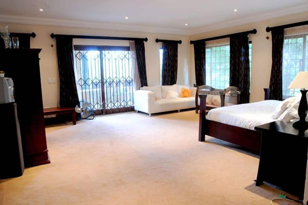 Ein Hotelzimmer mit Bett, Sofa, Schreibtisch und einem Fenster mit Vorhängen.