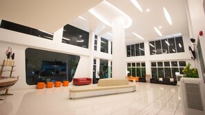 A spacious lobby with a central seating area, large windows, and a modern ceiling design. - Primetime Hotel (Chonburi)