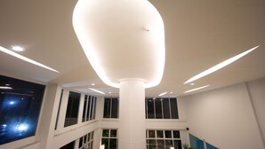 A modern interior with a central white column, multiple windows, and recessed lighting. - Primetime Hotel (Chonburi)
