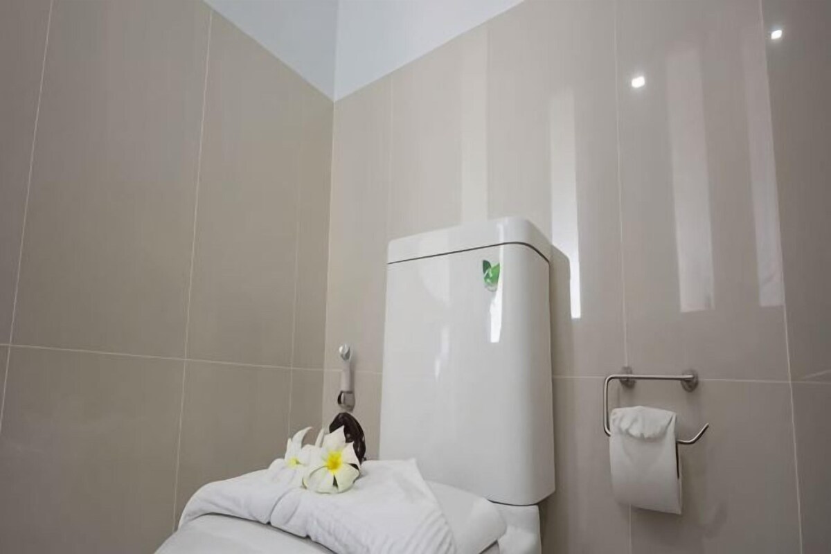 Un baño con inodoro, toallero y dispensador de papel higiénico.