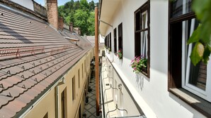 A narrow alleyway between buildings with tiled roofs and a white building with windows and hanging flower baskets.