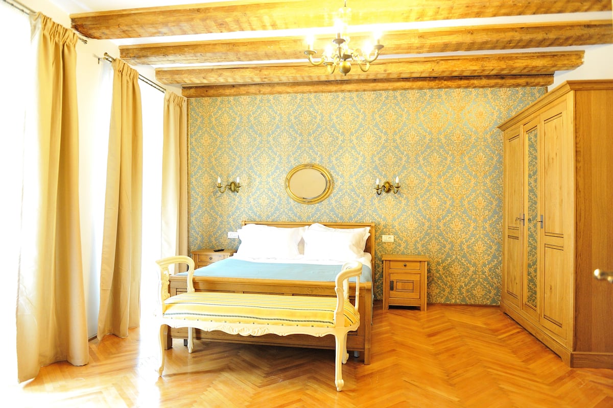 A bedroom with a wooden bed, a nightstand, a wardrobe, and a mirror on the wall.