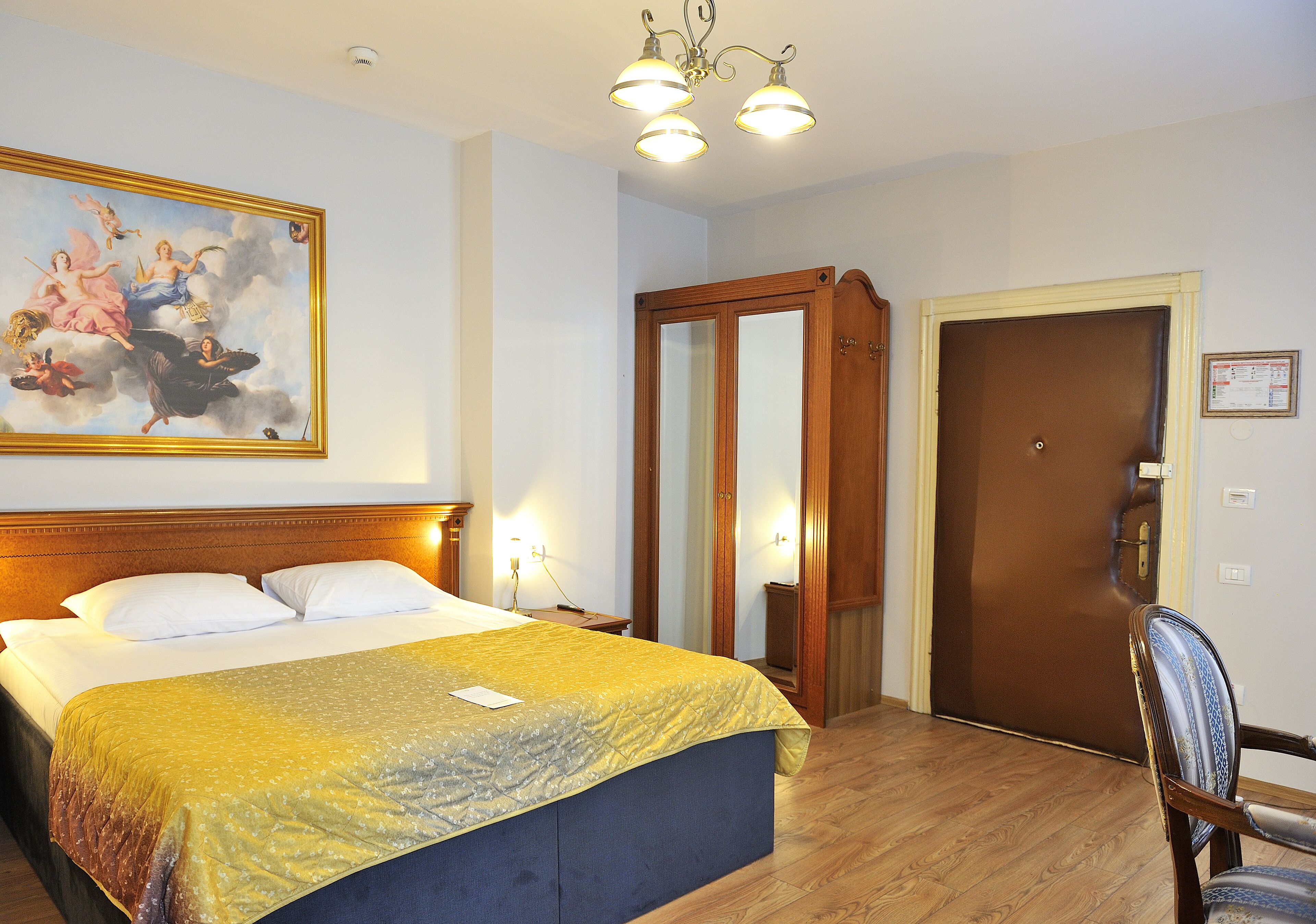 Una habitación de hotel con una cama grande, un armario de madera, una puerta y una silla.