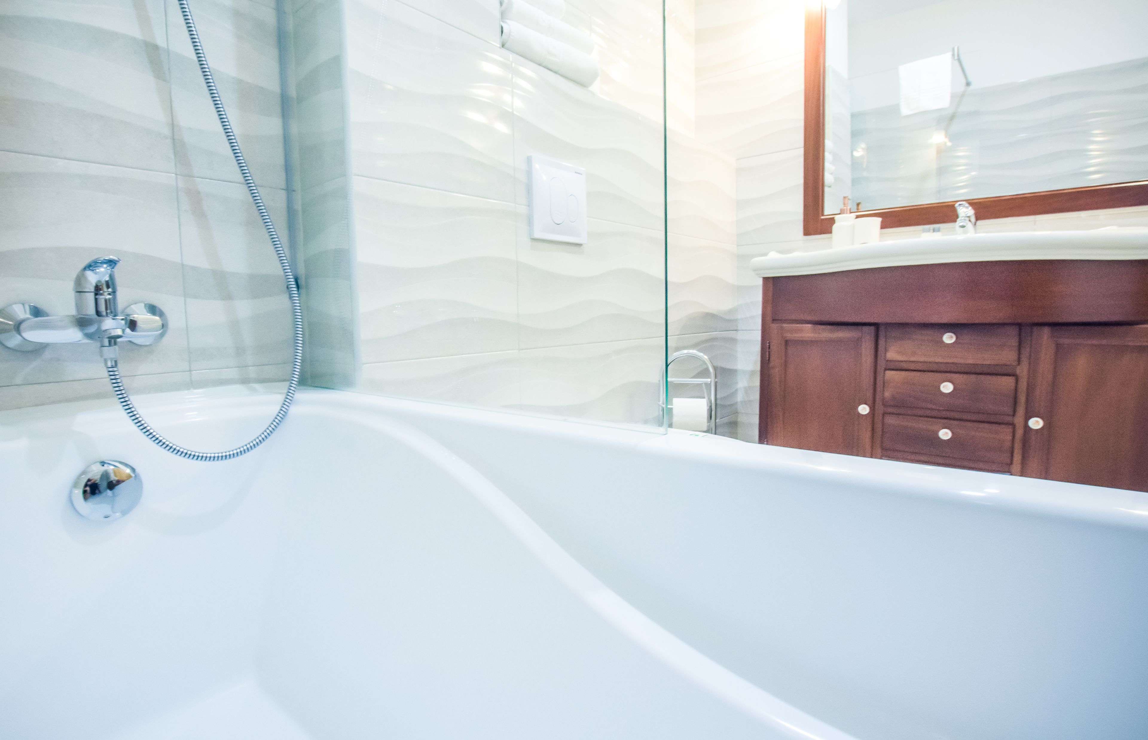 Un bagno moderno con una vasca freestanding, cabina doccia in vetro e un mobile vanitario in legno con specchio.