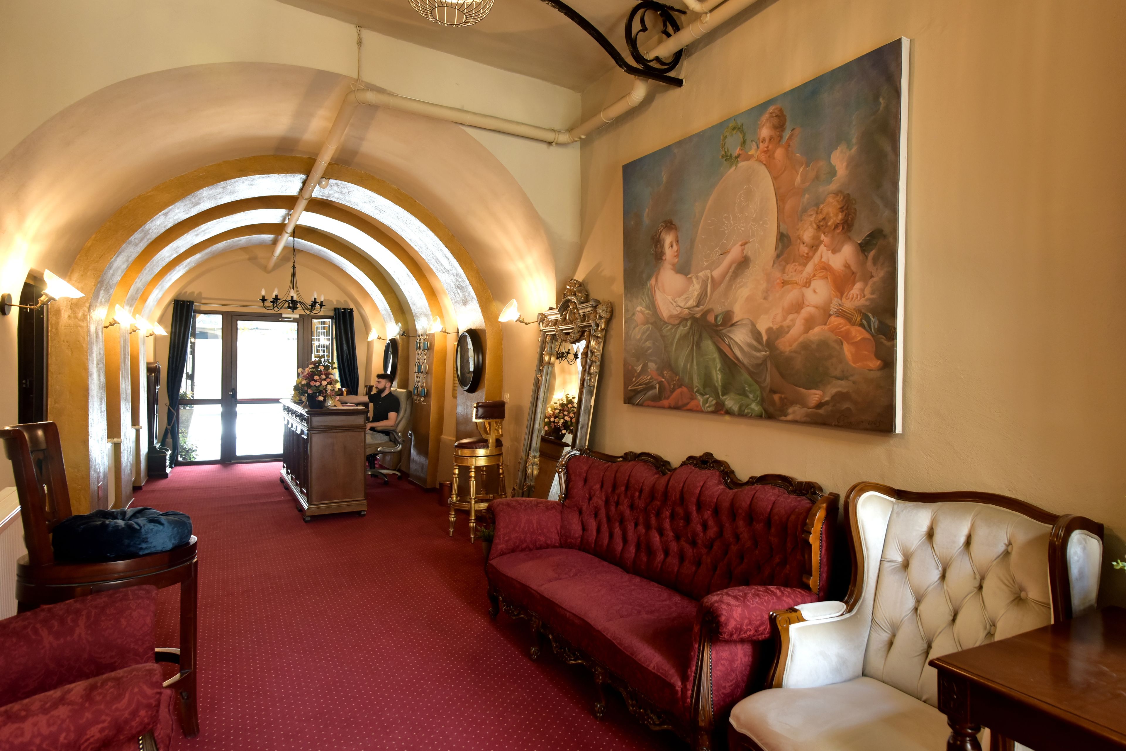 A grand room with a red carpet, a large painting, and a chandelier.