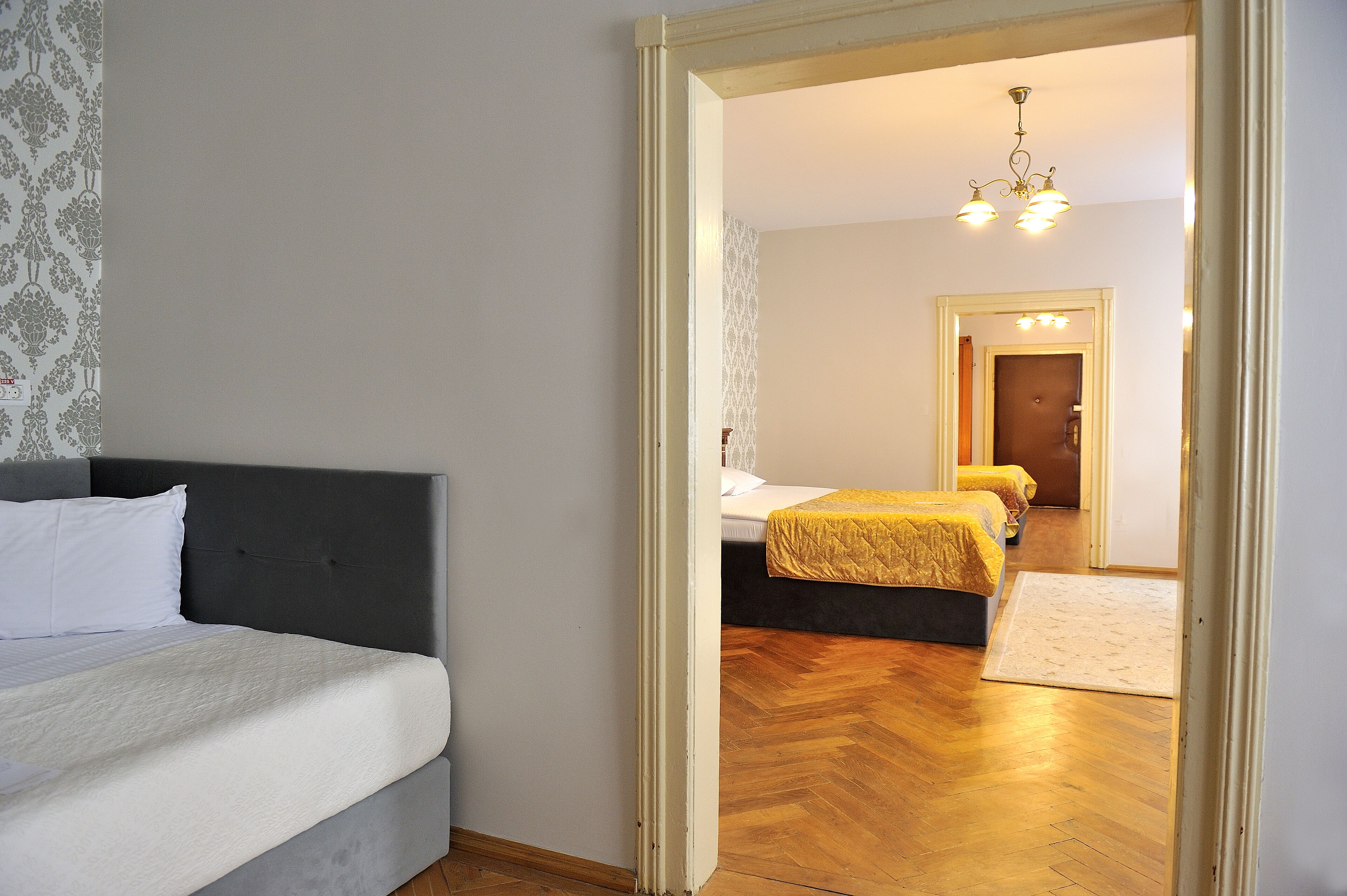 A bedroom with a bed, a mirror, and a door leading to another room.