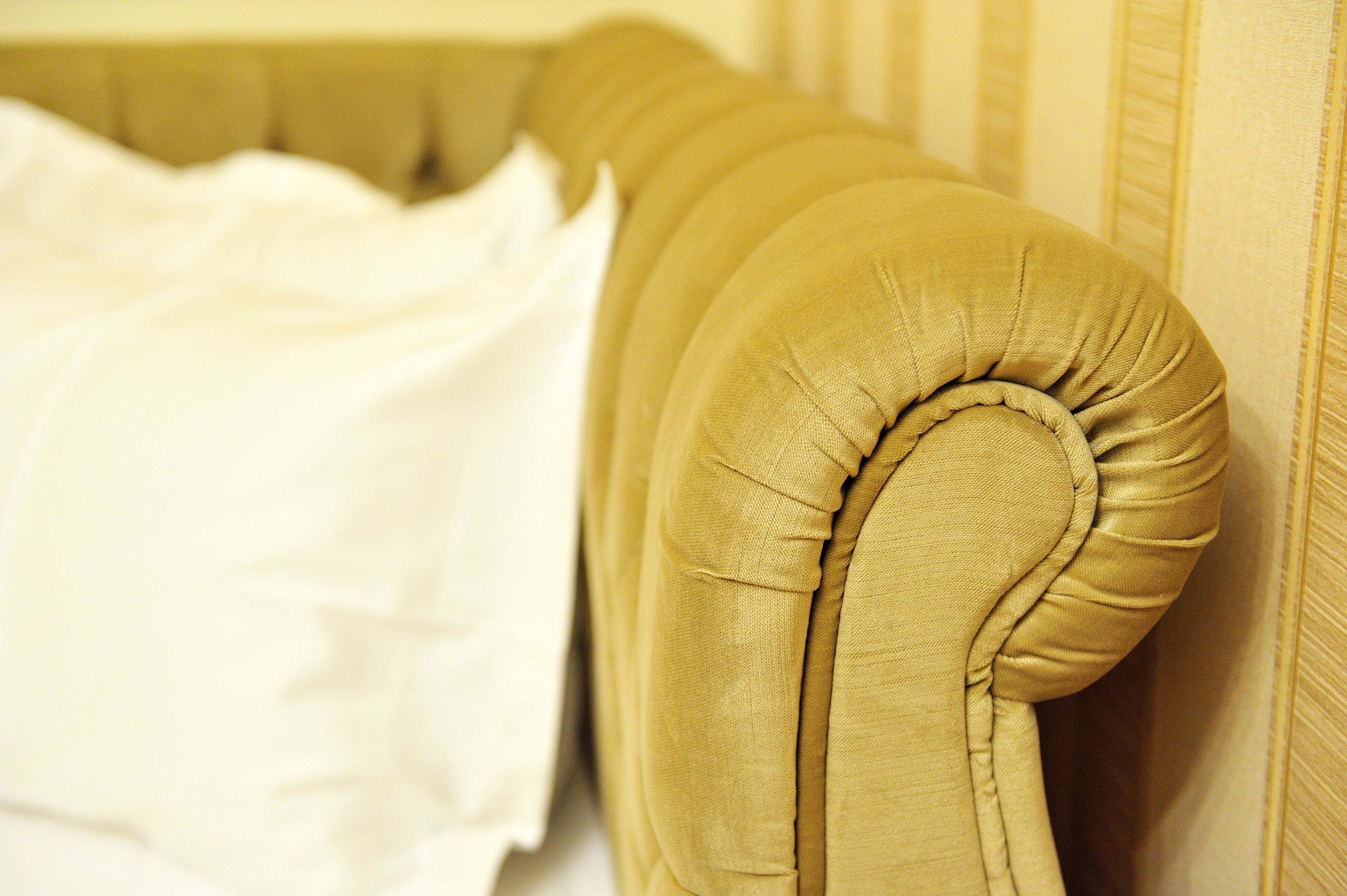 A close-up of a headboard with a tufted design and a white pillow.