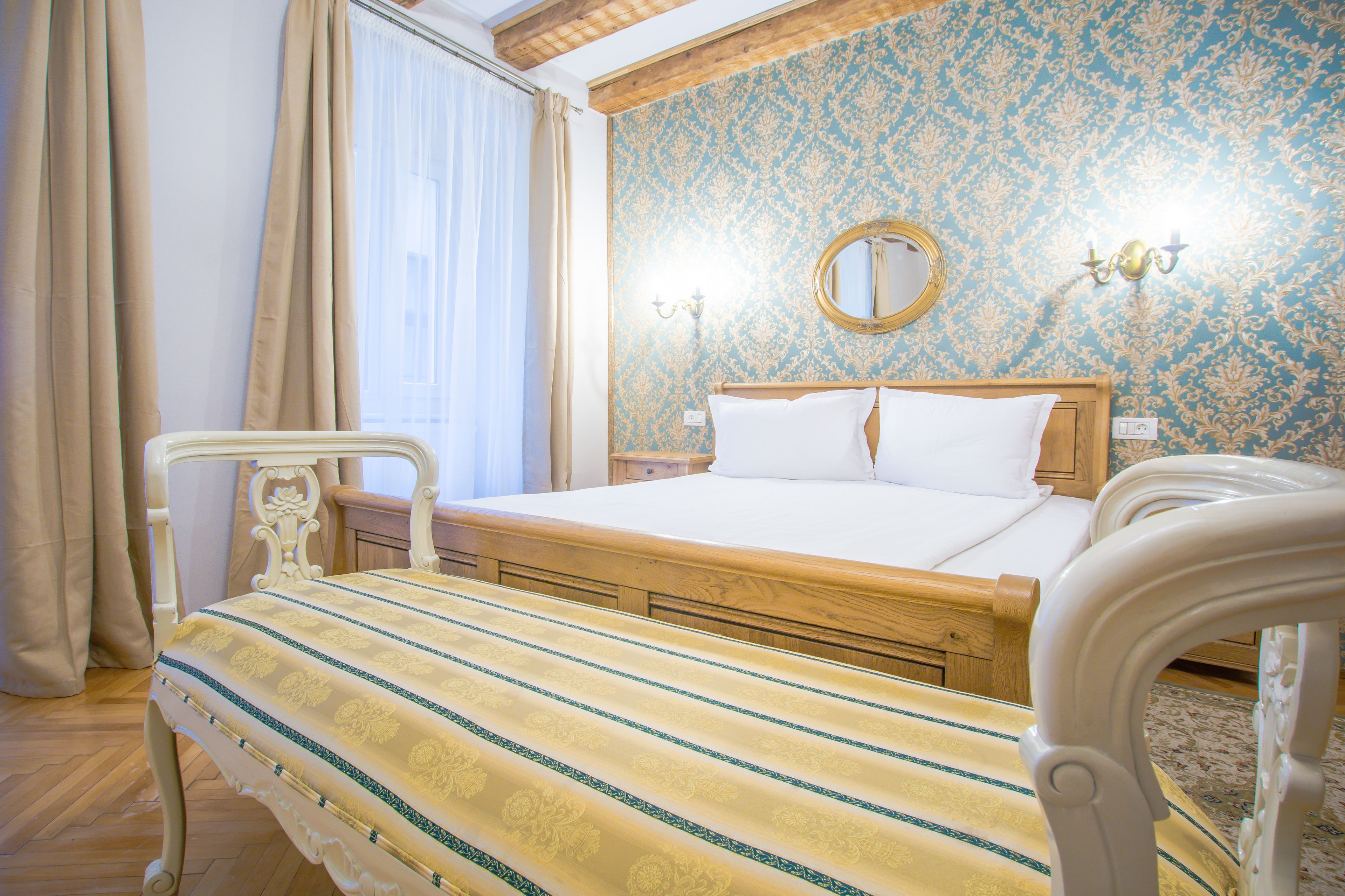 A bedroom with a wooden bed, a bedside table, a nightstand, and a mirror on the wall.