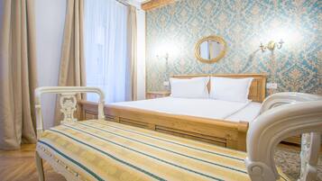 A bedroom with a wooden bed, a bedside table, a nightstand, and a mirror on the wall.