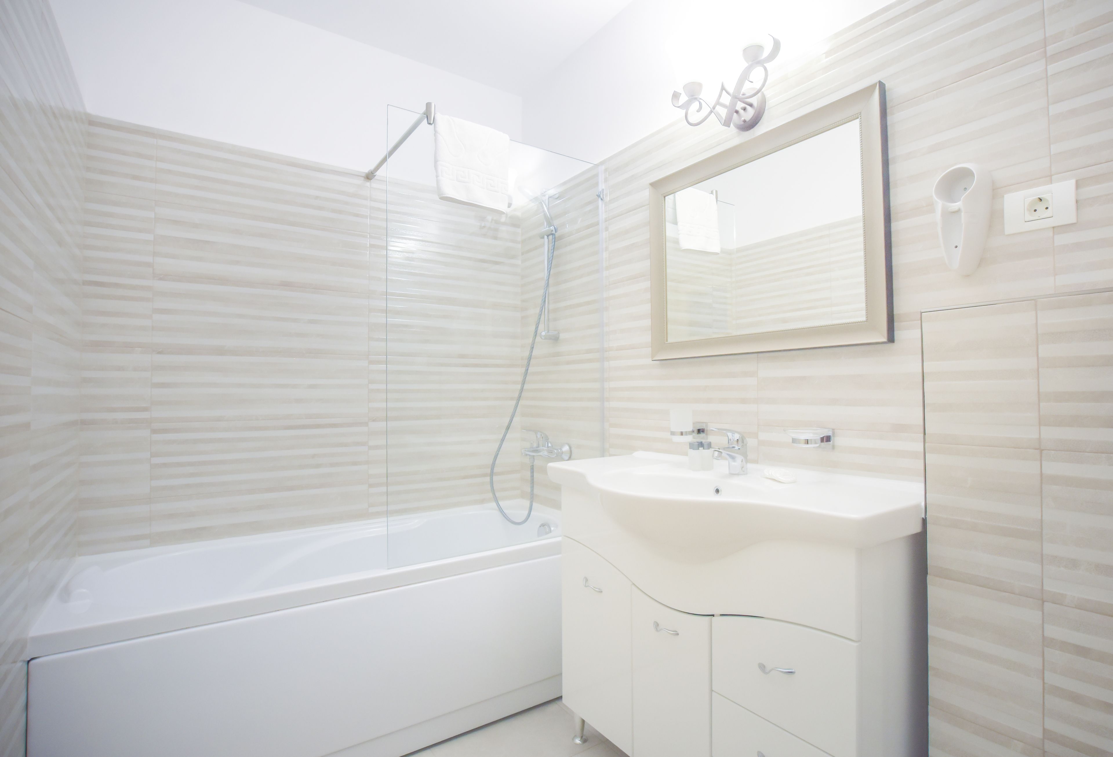 A modern bathroom with a white bathtub, a sink with a mirror above it, and a shower area.