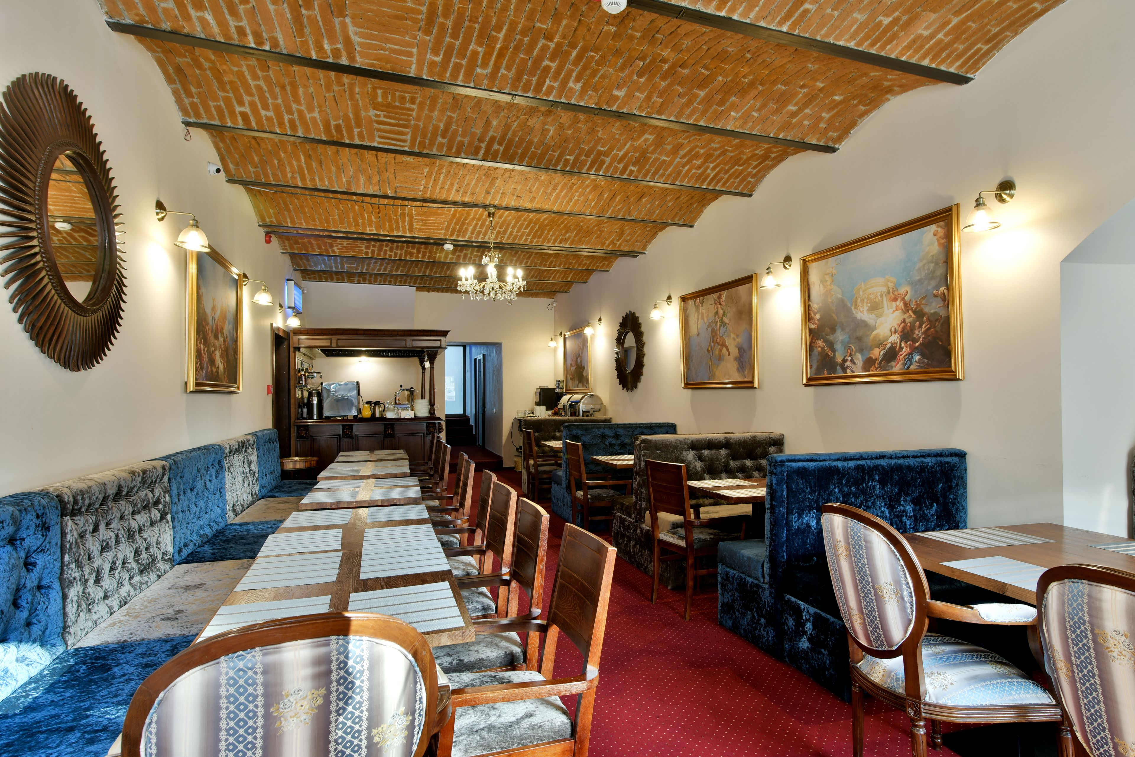 Ein Restaurant mit einer langen Theke, blauen Polsterbänken, Holzsesseln und einer Ziegeldecke.