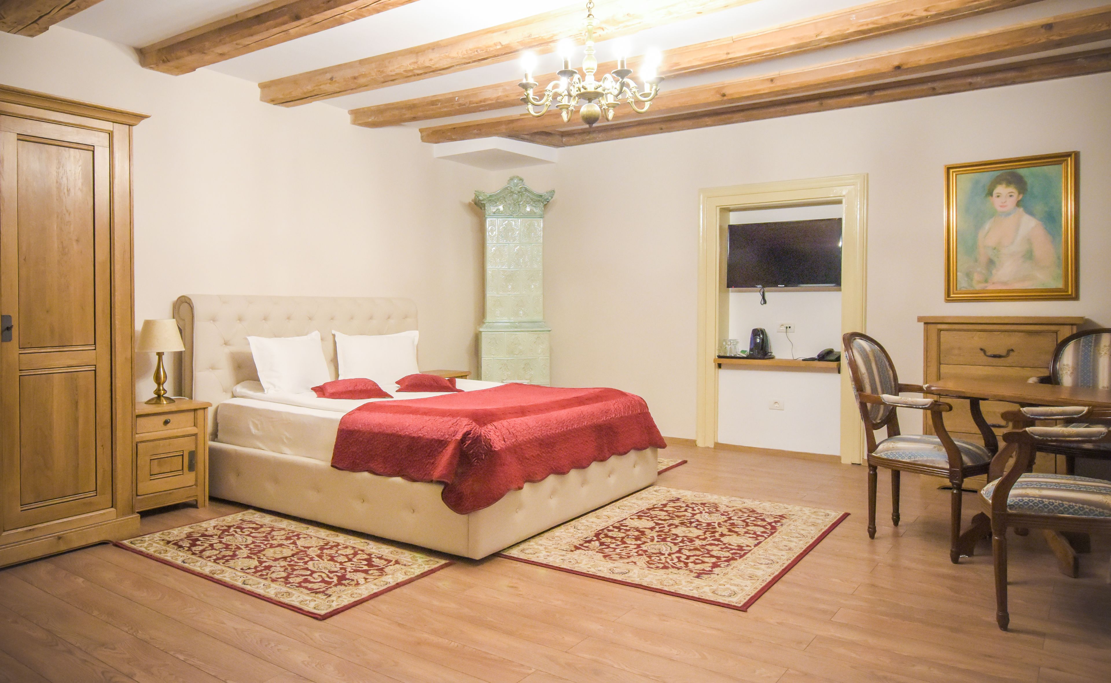 A bedroom with a bed, wooden furniture, a chandelier, and a painting.