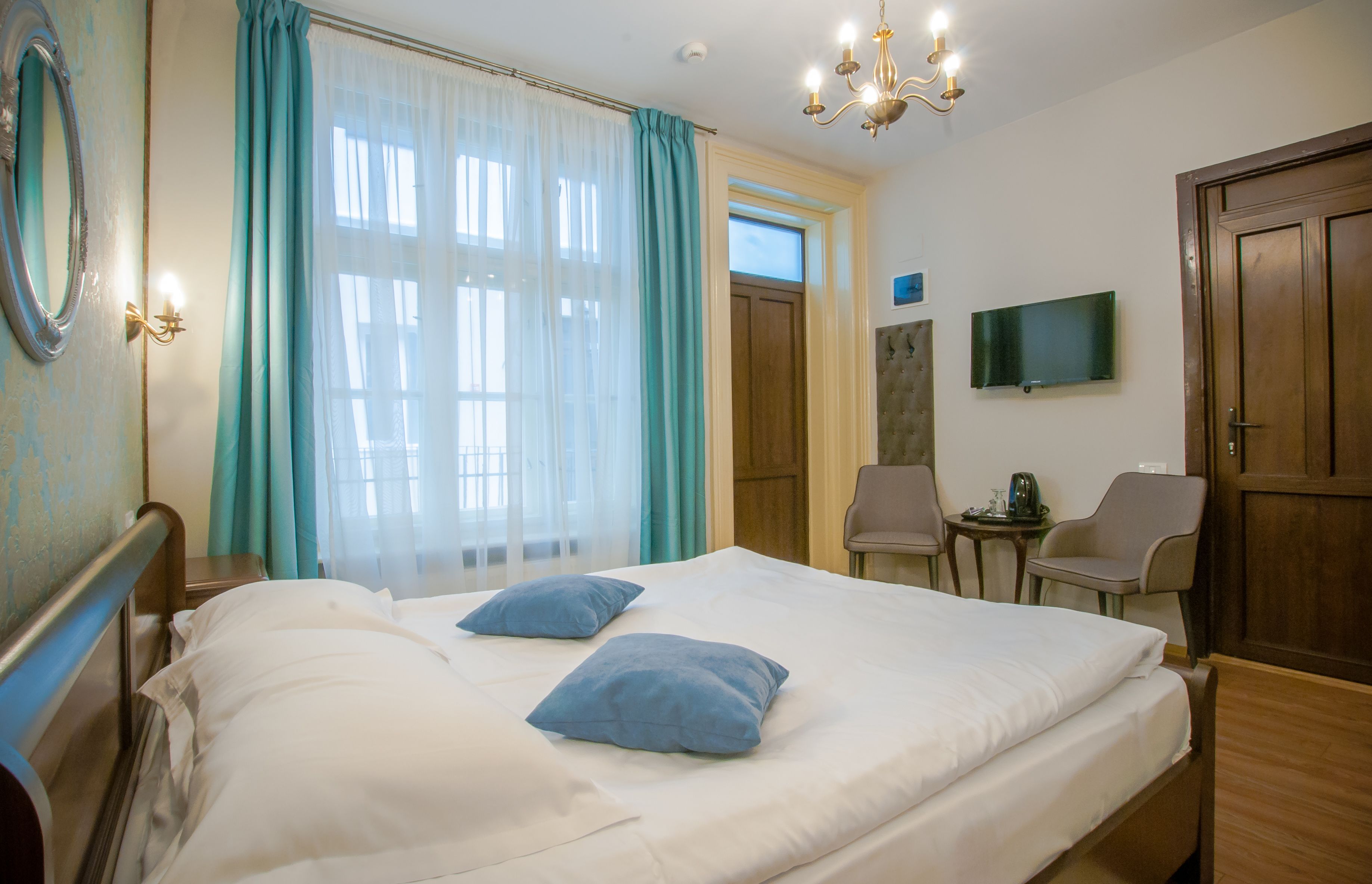 Una habitación de hotel con una cama, dos sillas, un televisor y una puerta de madera.