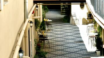 Un patio estrecho con suelo de baldosas, mobiliario exterior y plantas en macetas.