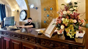 A reception desk with a telephone, a framed certificate, and a floral arrangement.