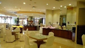 Un vestíbulo de hotel con mostrador de recepción, zona de estar y una barra con caja registradora.