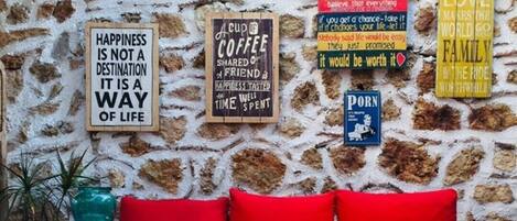 A colorful outdoor seating area with a stone wall, red cushions, and various motivational signs.